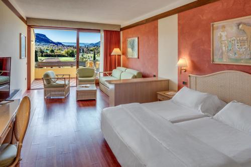 a hotel room with a bed and a living room at Poiano Garda Resort Hotel in Garda