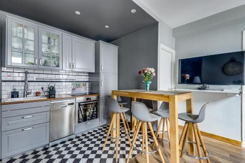 une cuisine avec des placards blancs, une table et des tabourets dans l'établissement AC & 10min from Marais & Fully equipped, à Paris