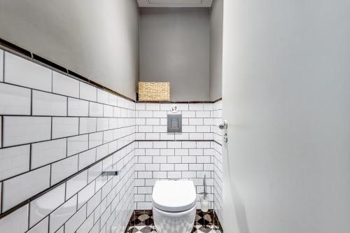 La salle de bains est pourvue de toilettes et d'un mur carrelé blanc. dans l'établissement AC & 10min from Marais & Fully equipped, à Paris