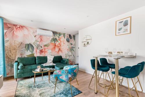 un salon avec un canapé vert et des fleurs roses dans l'établissement Beige Hospitalité - Salomé - Golden suite, à Saint-Étienne