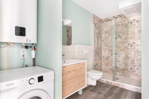 une salle de bain avec machine à laver et toilettes dans l'établissement Beige Hospitalité - Salomé - Golden suite, à Saint-Étienne
