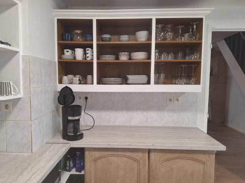 une cuisine avec un placard rempli d'assiettes et de vaisselle dans l'établissement VU sur campagne, maison proche Chatellerault, à Availles en Chatellerault