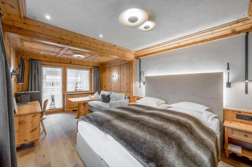 a bedroom with a large bed and a desk at Sport- und Genusshotel Silvretta in Ischgl