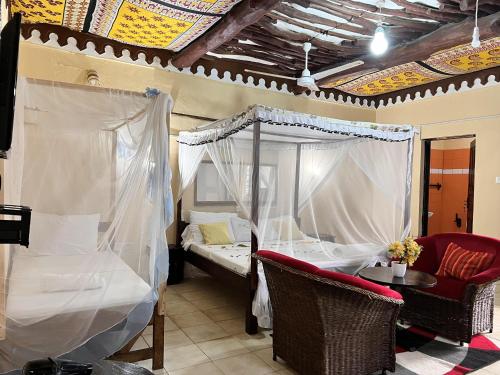 Un dormitorio con una cama con dosel y una mesa y sillas. en Diani Beach Luxury Retreat with 5 Bedrooms, en Diani Beach
