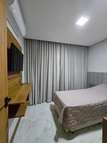 a hotel room with a bed and a television at Descanso na Serra in Areal