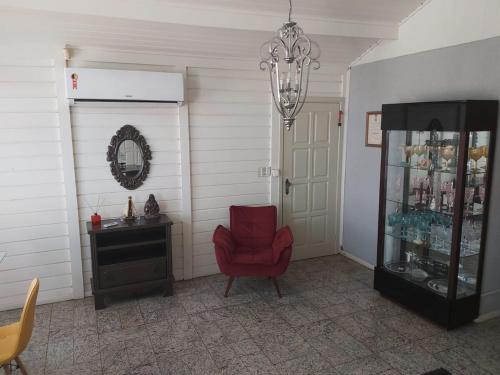 a room with a red chair and a glass cabinet at Beautiful house in the campoline the best neighborhood of sorocaba in Sorocaba