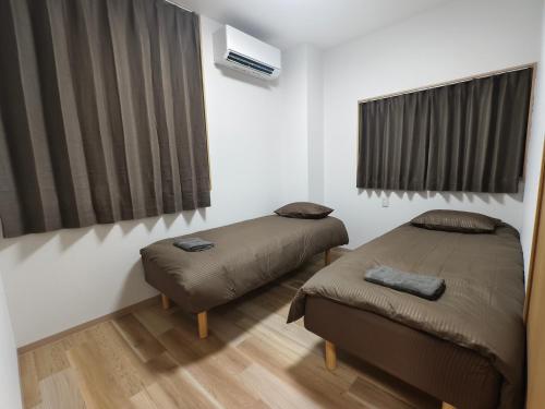 una camera con due letti e una finestra con tende di Issyuku Hotel Kotobuki Sanchome a Tokyo