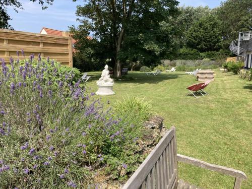 a garden with a statue and purple flowers at Hôtel Des Argousiers in Ambleteuse