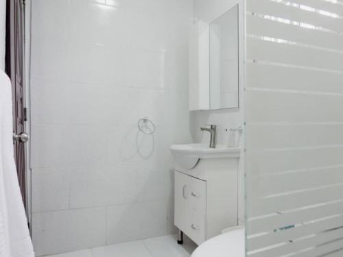 a white bathroom with a sink and a shower at Villas Hillside apt 4 in Santa Bárbara de Samaná