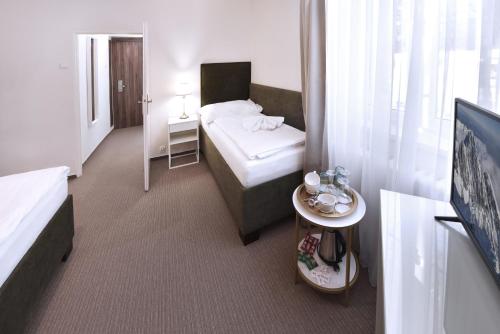 a hotel room with a bed and a table at APLEND Hotel Lujza Major in Tatranská Lomnica