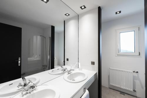 a bathroom with two sinks and a large mirror at Hotel Hita "Nature Experience" for all in Navacerrada