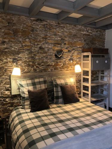 a bedroom with a bed with a stone wall at Le Cottage in Nantes