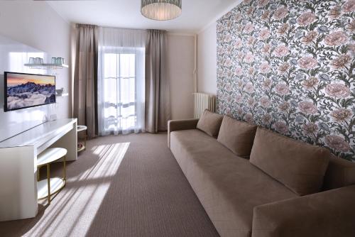a living room with a couch and a floral wall at APLEND Hotel Lujza Major in Tatranská Lomnica