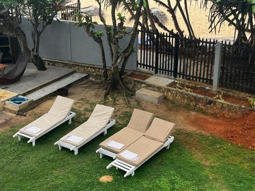 two lounge chairs on the grass next to a fence at Strandvilla Kandu Haus Yin bei Hikka in Dodanduwa