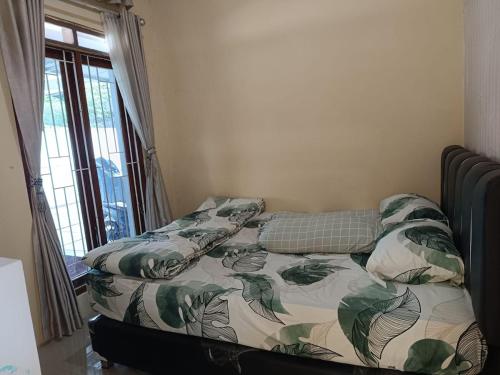 1 cama en un dormitorio con colcha de hojas en Than's Homestay Wonosobo, en Wonosobo