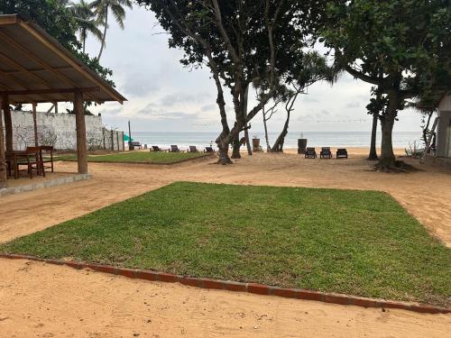 a field of grass on a beach next to the ocean at Villa ArthurCC in Hikkaduwa