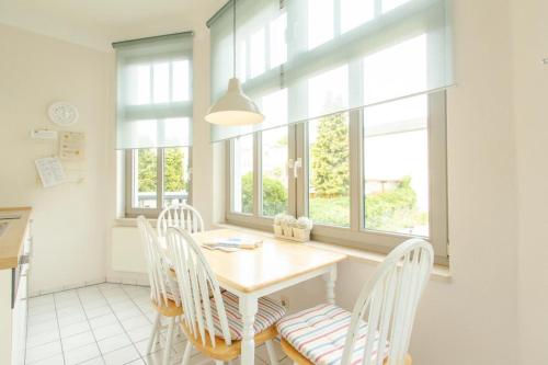a dining room with a table and chairs and windows at 2 Meerestraum in Rostock