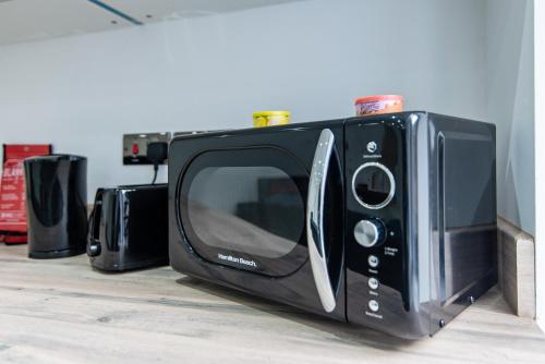 einem schwarzen Mikrowellenherd auf einer Theke in der Unterkunft 1-Bed Apartment near Bradford City Centre in Bradford