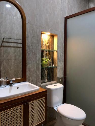 a bathroom with a white toilet and a sink at Van Bloemen 1881 Resort in Kembanglimus