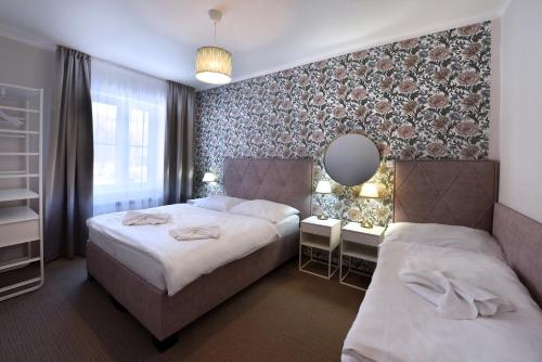 a bedroom with two beds and a mirror at APLEND Hotel Lujza Major in Tatranská Lomnica