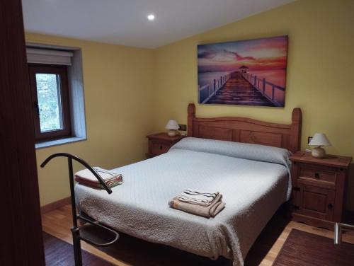 a bedroom with a bed with a painting on the wall at Casa Alicia in Carnota