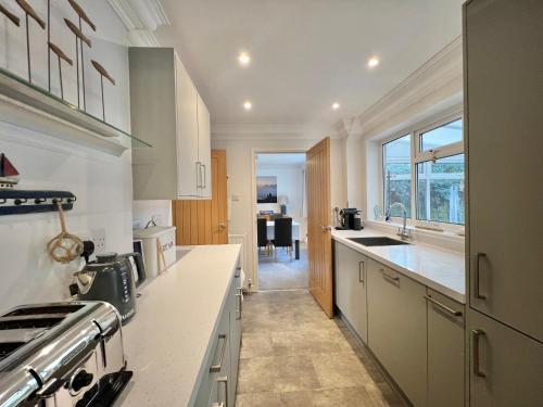 a kitchen with white cabinets and a sink and a stove at 4 Bed Retreat with Balcony & Estuary views in Exeter