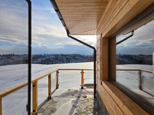 a view of the snow from the window of a house at LK Mountain Residence segmenty z prywatnym jacuzzi i widokami na góry i jezioro in Falsztyn