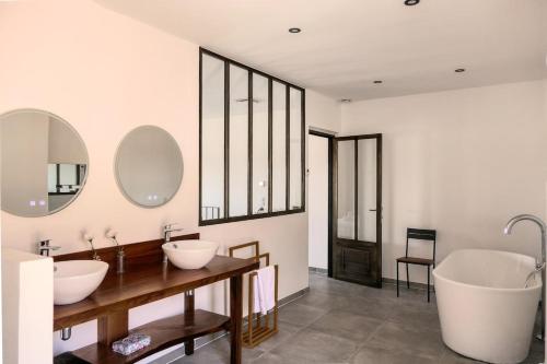 une salle de bain avec deux lavabos et deux miroirs dans l'établissement Maison cœur de village piscine 6 personnes, à Vacqueyras