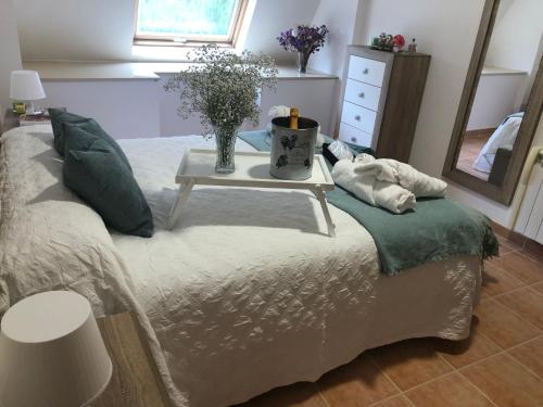 a bed with a table with a vase of flowers on it at Ático de Carmen in Cee