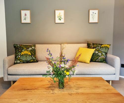 a living room with a couch and a table with flowers at Ferienhaus direkt am See Uckermark in Templin
