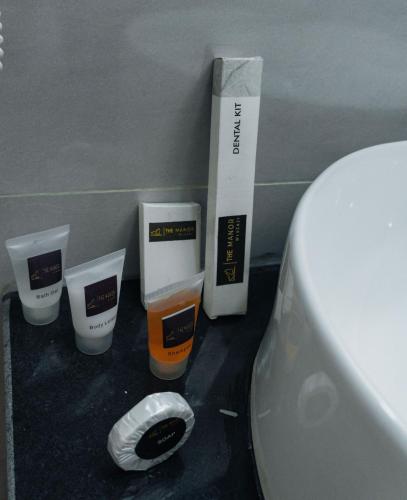 a bathroom with a toilet and three cups of orange liquid at The Manor Hotel by Luckzi in Owerri