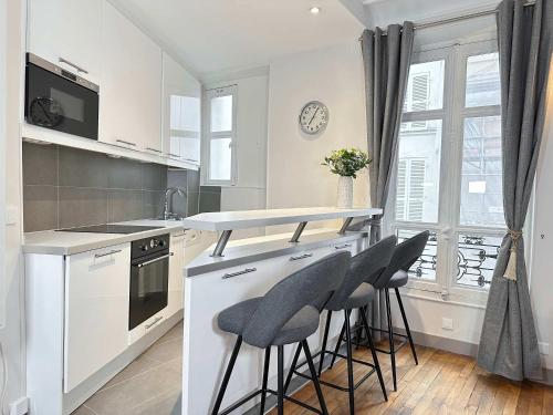 une cuisine avec un comptoir et des tabourets sur un îlot de cuisine dans l'établissement Lovely Apartment in Le Marais, à Paris
