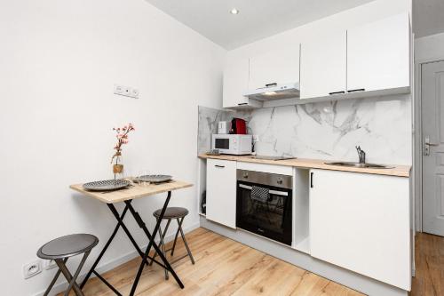 une cuisine avec des armoires blanches et une table en bois dans l'établissement VILLA FLORENTINE I - Frontière Monaco - Agréable deux pièces - PARKING, à Beausoleil