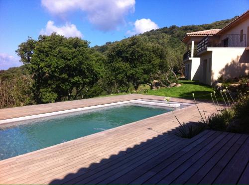 une piscine avec une terrasse en bois à côté d'une maison dans l'établissement Olmeto Villa, à Olmeto