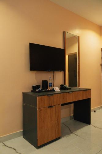 a desk with a flat screen tv on a wall at The Manor Hotel by Luckzi in Owerri