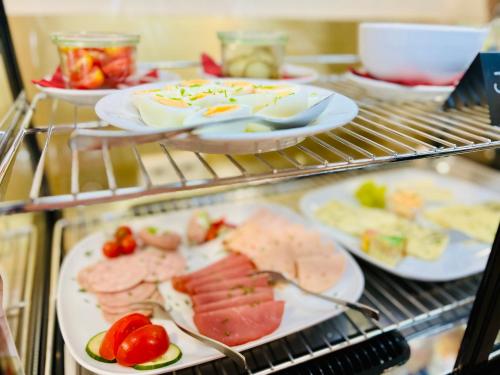 ein Buffet mit Fleischgerichten und Gemüse darauf in der Unterkunft Rosengarten Apartments Fürth, Moderne Serviced Apartments in Citylage, ganze Ferienwohnung 50 m2, nahe Nürnberg, Metro, Sauna, Frühstück & Parkplatz in Fürth