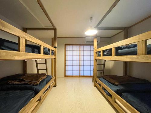 two bunk beds in a room with a window at Guesthouse NALUノ道 in Kobe