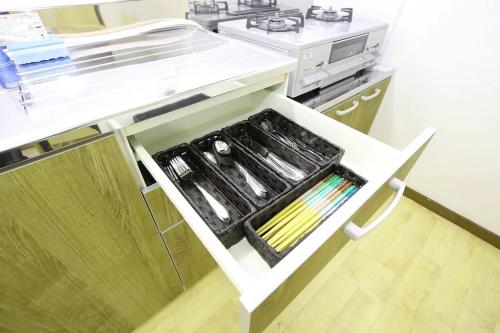 a kitchen with a counter with a drawer with utensils at Masaru House in Osaka