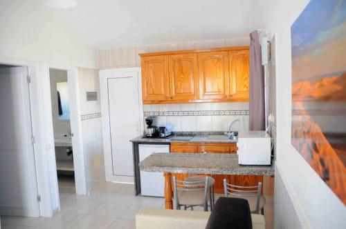 a kitchen with wooden cabinets and a counter top at Bungalows Los Arcos in Playa del Ingles