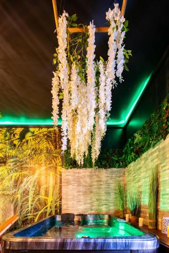 un lustre avec des fleurs blanches suspendues au-dessus d'une piscine dans l'établissement Sweet Uni'vert Jacuzzi, à Le Breuil