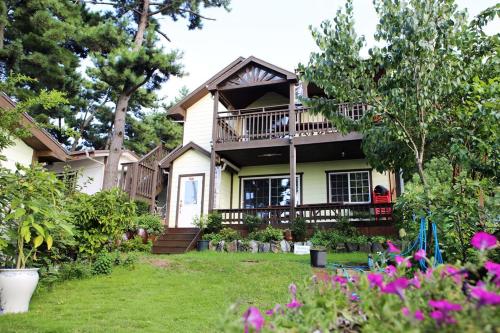a house with a balcony and a yard with flowers at Modni Pension in Taean