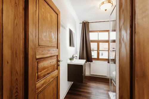 a bathroom with a wooden door and a sink at Gutshof zu Quedlinburg in Quedlinburg