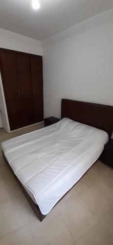 a bedroom with a large bed with white sheets at Quiet spacious apartment in Larache