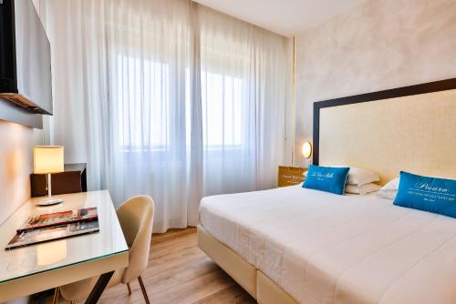 a hotel room with a bed and a desk and a bed at UNAHOTELS Imperial Sport Hotel in Pesaro