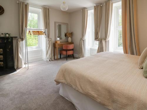 a bedroom with a bed and a desk and windows at Serenity House, The Retreat in Llangammarch Wells