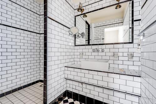 La salle de bains est pourvue de carrelage blanc, d'un lavabo et d'un miroir. dans l'établissement AC & 10min from Marais l Center of Paris, à Paris