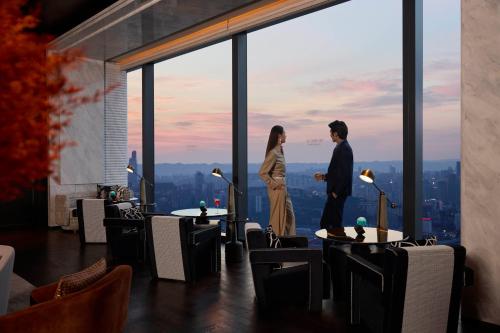 a man and a woman standing in a room with a view at Conrad Chongqing - Indulge in the magical 8D city landscape in Chongqing