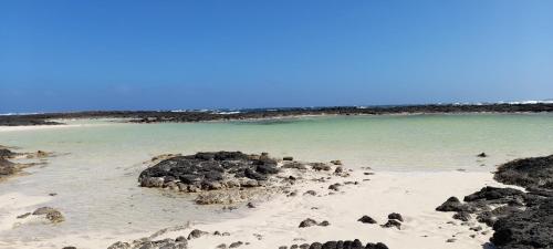 einen Strand mit einigen Felsen im Wasser in der Unterkunft Casa Vale in Majanicho
