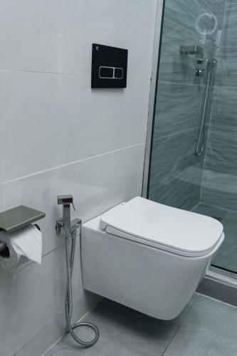 a white toilet in a bathroom with a shower at The Manor Hotel by Luckzi in Owerri