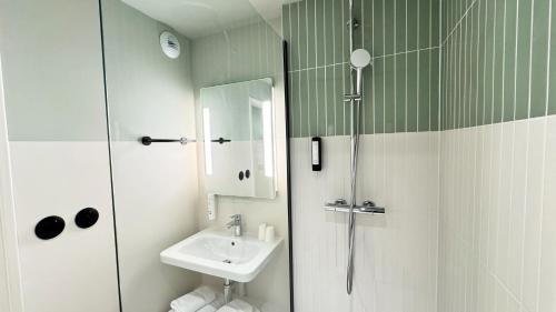 a small bathroom with a sink and a shower at Kyriad Prestige Compiègne Hotel & Spa in Compiègne